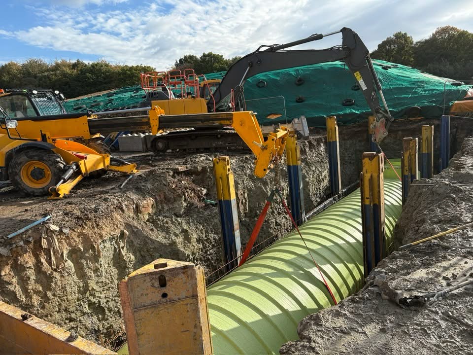 Excavator installing a large underground tank in a prepared excavation